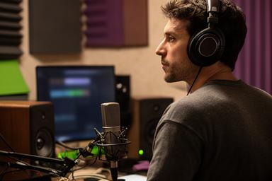 Music producer listening closely in a compact studio with acoustic treatment